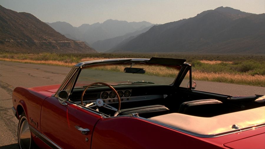 Empty red convertible on a mountain road